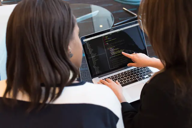 Two people reviewing code together on a laptop