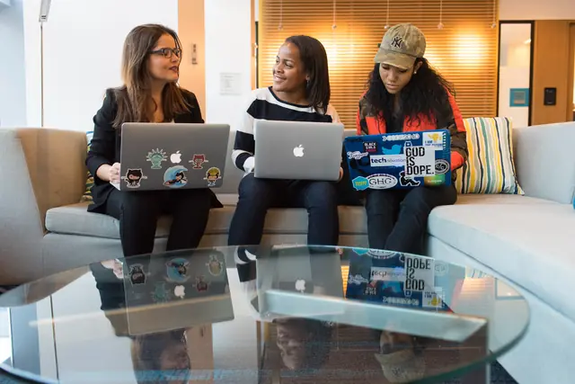 Three learners working on laptops together on a sofa