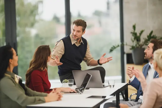 A team meeting around a table with laptops in a bright office